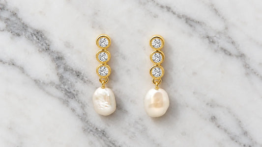 aBaroque Pearl Drop Earrings in gold-plated silver with irregular freshwater pearls on white marble