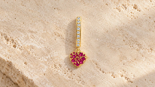 aSymbol Single Hoop in gold-plated silver with a heart of red stones on light travertine stone