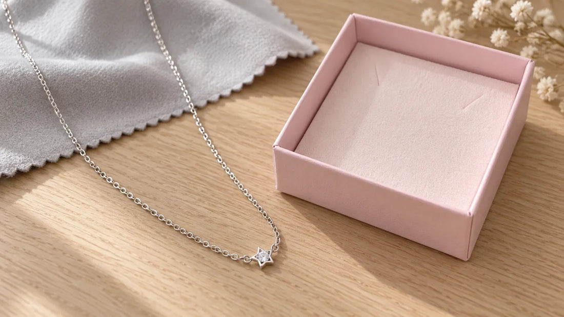 Star Collier Necklace in sterling silver with a polishing cloth and jewelry box on light oak