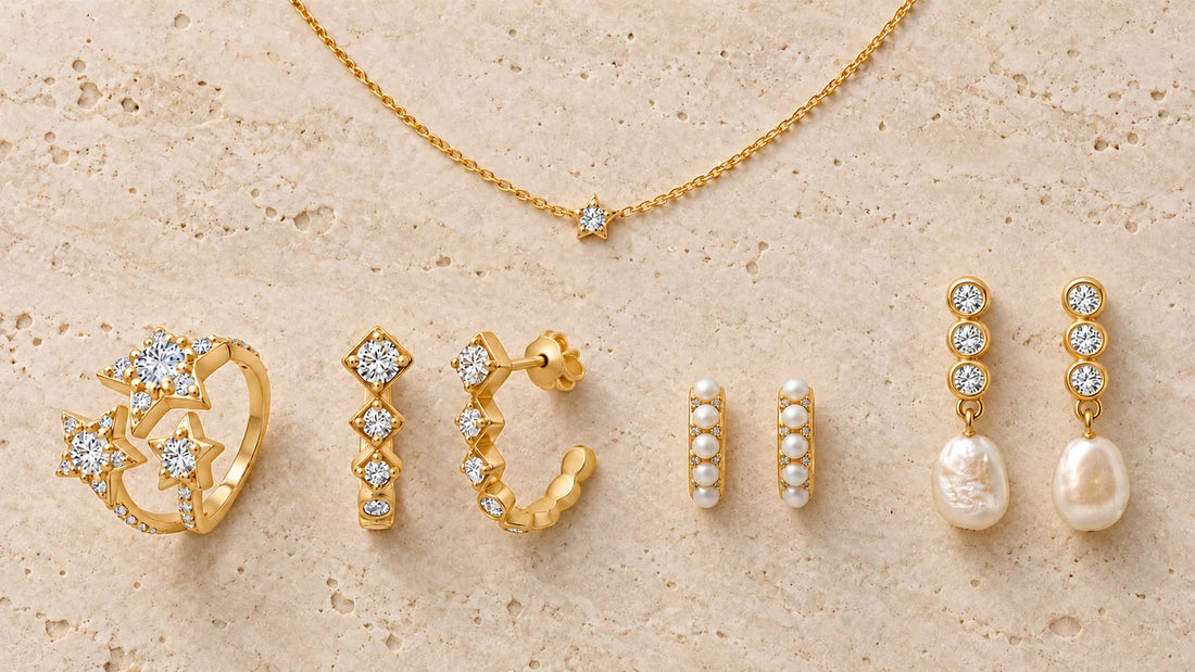 Gold-plated jewelry of different types, hoops, huggies, pearl earrings, an open ring and a necklace, arranged on light travertine stone